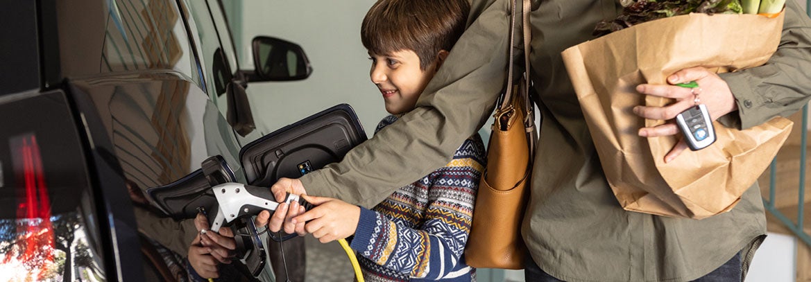 young family charging electric vehicle