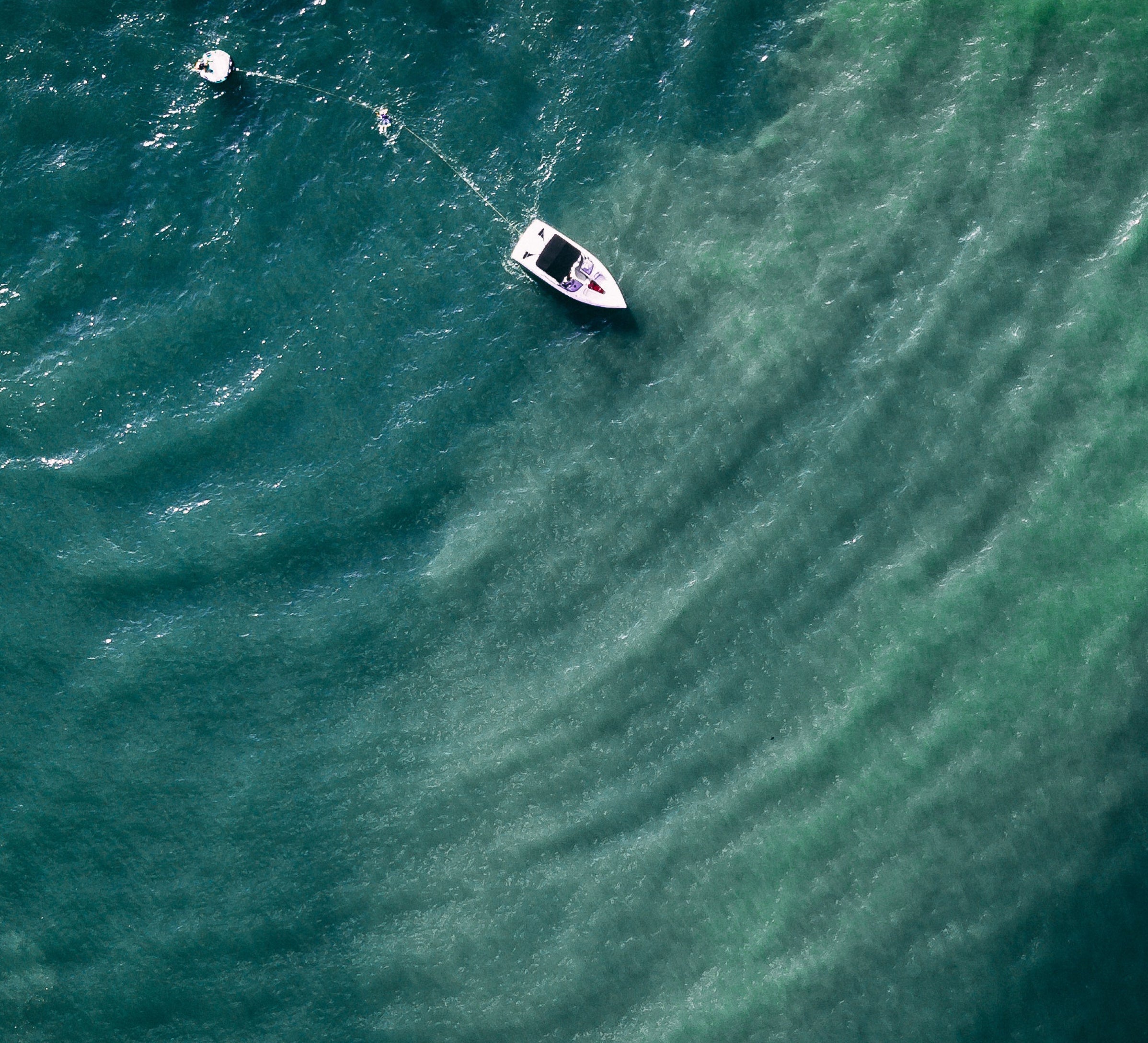 Boat pulling raft through clear water